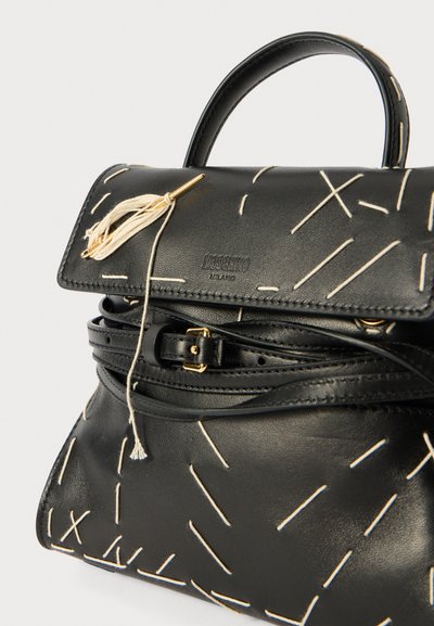 Black leather handbag featuring a structured shape, decorative white stitching, a top handle, and a gold-tone accent with a tassel detail.