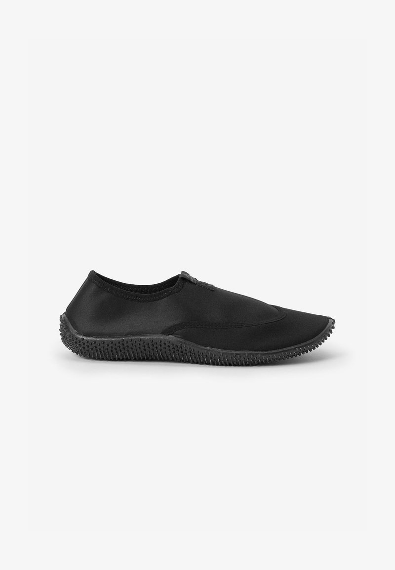 Chaussure noire et flexible avec un matériau supérieur lisse et une semelle en caoutchouc texturée présentant de petites proéminences pour une meilleure adhérence. Design élégant avec des accents minimaux.