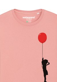 T-shirt en coton rose avec une silhouette noire d'un enfant tenant un ballon rouge. Présente un col rond et un tissu doux et texturé.