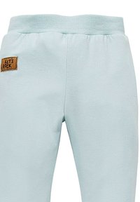 Helle blaue Jogginghose aus weichem Material, mit einem gerippten Bund und einem braunen Patch mit dem Text "LET'S ROCK".