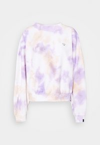 Långärmad kort sweatshirt med mönster i lila och beige batik och liten logga framtill på vit bakgrund.