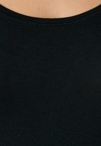 Top de tirantes negro con cuello redondo, hecho de una tela elástica y suave. Sin logotipos ni adornos visibles.