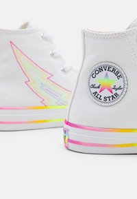 Weiße High-Top-Sneaker mit irisierendem Blitz und einem Farbverlauf an der Sohle. Verfügt über ein rundes Logo-Patch an der Seite.