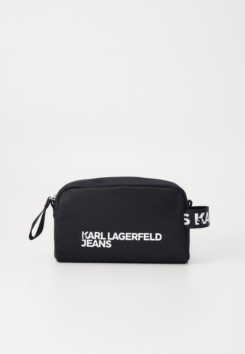 Juodas nailono maišelis su sidabro užtrauktuku, ant kurio yra užrašas "KARL LAGERFELD JEANS" baltomis raidėmis. Maišelas turi rankeną su kontrastinga juodai balta juosta.