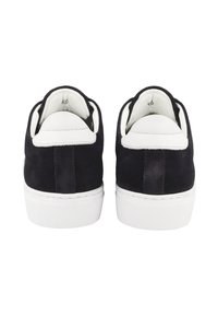Pair of black suede sneakers with white heel tabs and thick white rubber soles, shown from the back on a white background.