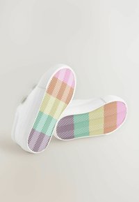 Baskets blanches avec des semelles en caoutchouc texturé affichant un dégradé de couleurs pastel : rose, lavande, vert, jaune et orange dans un motif en zigzag.