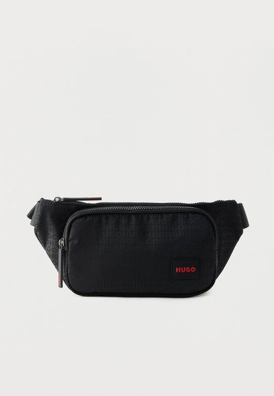 Sac banane rectangulaire noir avec deux compartiments zippés, motif logo embossé discret et étiquette rouge "HUGO" sur la poche avant.