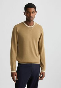 Hellbrauner Strickpullover mit Rundhalsausschnitt, ausgestattet mit einem strukturierten Kragen und kontrastierenden weißen Akzenten an den Bündchen und dem Saum.