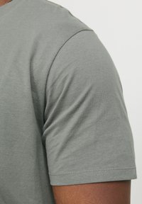 Gray short-sleeve t-shirt made of soft fabric, featuring a smooth texture and a crew neck with stitched detailing along the hem.
