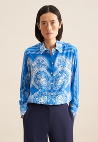 Camicia a maniche lunghe blu con motivo paisley bianco, dotata di colletto e bottoni sul davanti, realizzata in un tessuto liscio.
