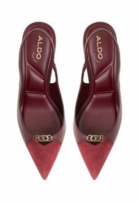 Burgundy högklackade slingback-skor med spetsig tå och framsidan i mocka. Har en guldfärgad spänne och andningsbar innerkudde.