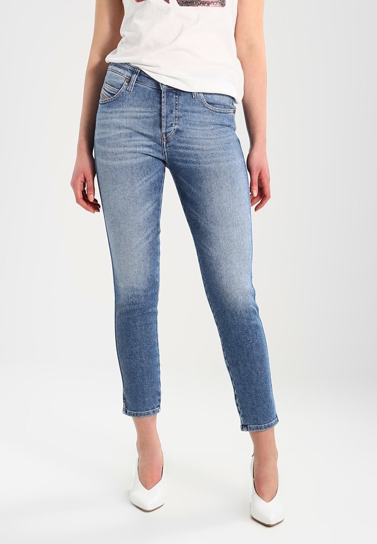 Ljusblå smala jeans av denim med blekta detaljer, fem fickor och midjehöjd. Bärs med en vit topp och vita klackskor.