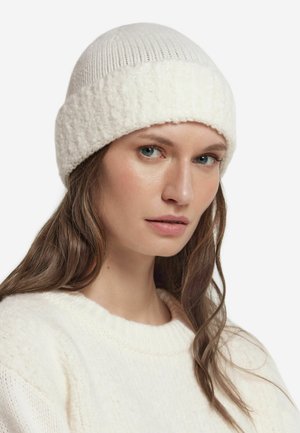 Biała dziana czapka z prążkowaną fakturą na górze i puszystym, teksturowanym mankietem. Miękki, ciepły materiał z przytulnym, dopasowanym krojem.