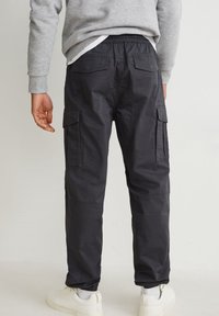 Svarta cargosbyxor med elastisk midja, flera sidofickor och avsmalnande ben. Tillverkade av ett lätt och hållbart tyg.