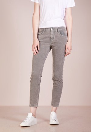 Pantalons en velours côtelé gris au design ajusté, taille mi-haute, poches avant et texture lisse, associés à des baskets blanches.