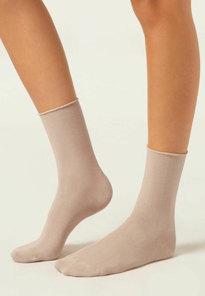 Beige Knöchelsocken aus glattem, leichtem Material mit einem schlichten Design, das einen gerippten Saum und eine nahtlose Zehenkonstruktion aufweist.