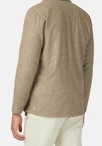 Brun skjorta jacka i fiskbensmönster med skräddarsydd passform, har en rundad nederkant, en ficka och kontrasterande tygtextur.