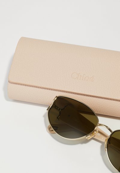 Gafas de sol Chloé con lentes de color verde oliva, herrajes dorados y un estuche de cuero texturizado de color rosa pálido con el logotipo "Chloé" en relieve.