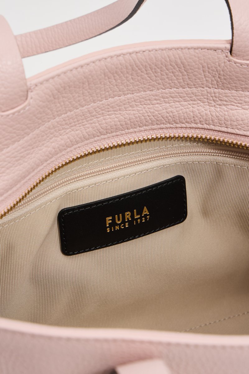 Różowa skórzana torebka od środka z kremową podszewką, z zamkiem błyskawicznym oraz czarną metką z wypukłym napisem "FURLA SINCE 1927."