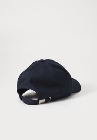 Sötétkék pamut baseball sapka ívelt féméllel, állítható pánttal a hátsó részen és varrott szellőző lyukakkal.