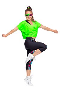 Neon zelena skraćena majica, crne tajice s raznobojnim geometrijskim uzorcima i bijeli visoki tenisice. Model nosi ružičaste naočale i rep.