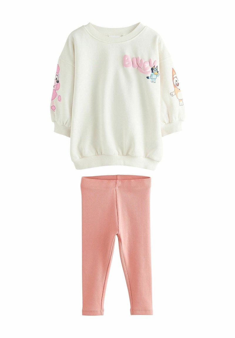 Sudadera de forro polar blanca con personajes de dibujos animados y texto rosa, combinada con leggings rosas de canalé. Textura suave, corte relajado y mangas largas.