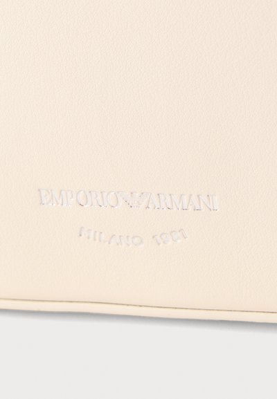 Υφή από κρεμ δέρμα με ανάγλυφο λογότυπο Emporio Armani και κείμενο "Milano 1981" από κάτω.