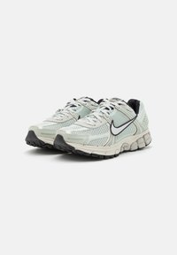 Light green running shoes with mesh fabric, black accents, and a cushioned sole. Features a white Swoosh logo and textured surfaces.
