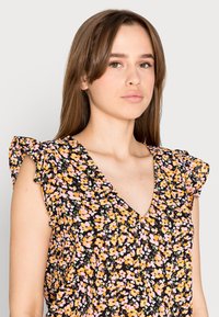 Blusa preta florido com decote em V, mangas curtas com babados e um padrão de flores rosa e laranja com detalhes verdes.