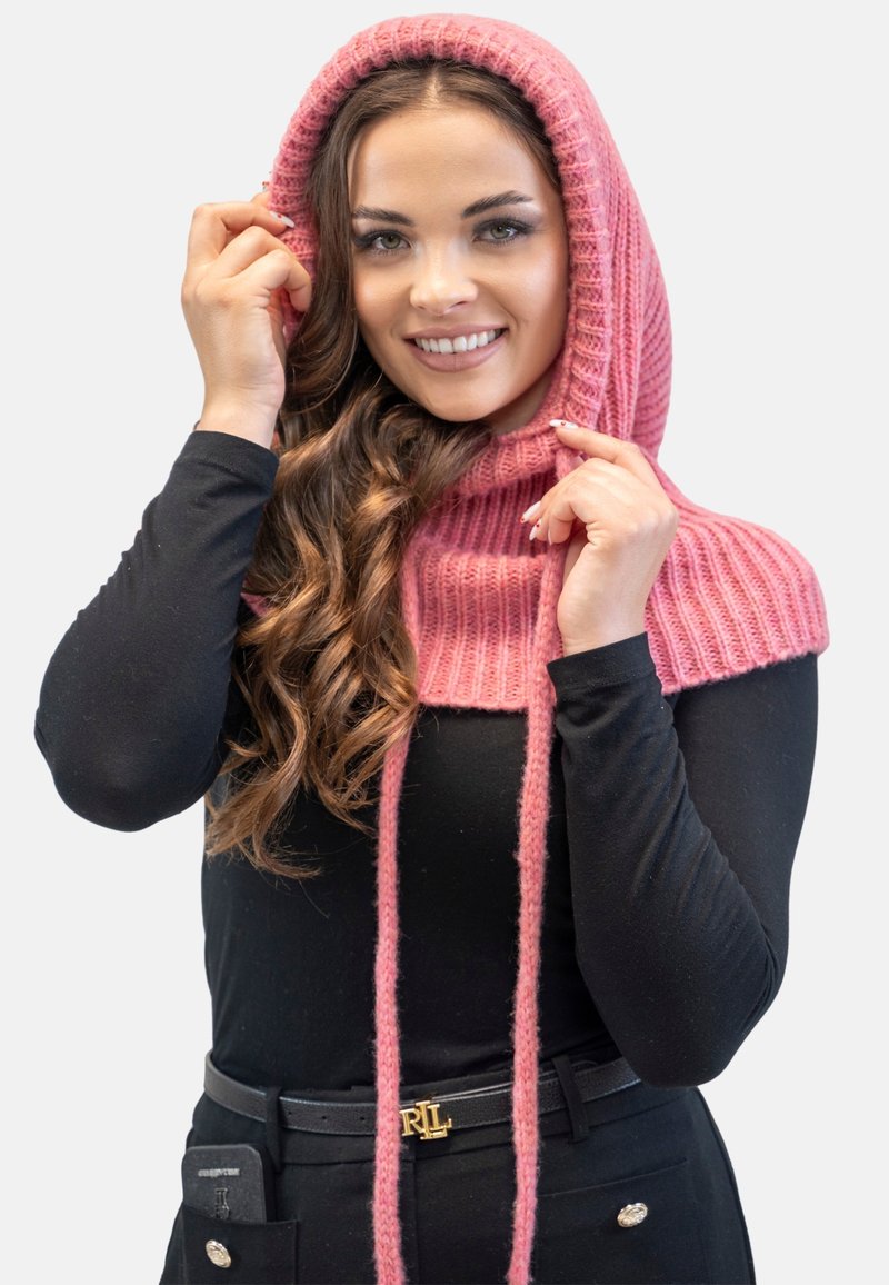 Sciarpa a cappuccio lavorata a maglia rosa con texture a coste, dotata di lunghe fascette, indossata sopra un top nero a maniche lunghe. Tessuto liscio e colore vivace.