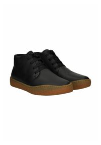 Bottines en cuir noir avec un bout arrondi, un laçage sur le devant et une semelle en caoutchouc brun texturé. Fini lisse sans motifs visibles.