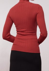 Czerwony sweter z golfem, w ribby, o dopasowanej sylwetce i długich rękawach. Tekstura posiada wzory w warkocz oraz smukły pas.