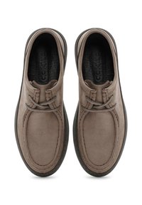 Chaussures en suede marron avec un bout rond, des lacets texturés et une semelle en caoutchouc noire contrastante. Conception légère avec des détails de couture minimaux.