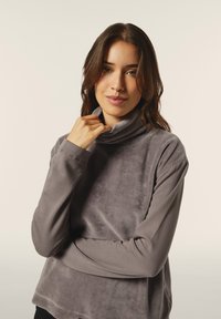 Top gris de manga larga con cuello de tortuga hecho de un material suave y aterciopelado. Presenta un corte holgado y un cuello enrollado, con detalles de costura sutil.