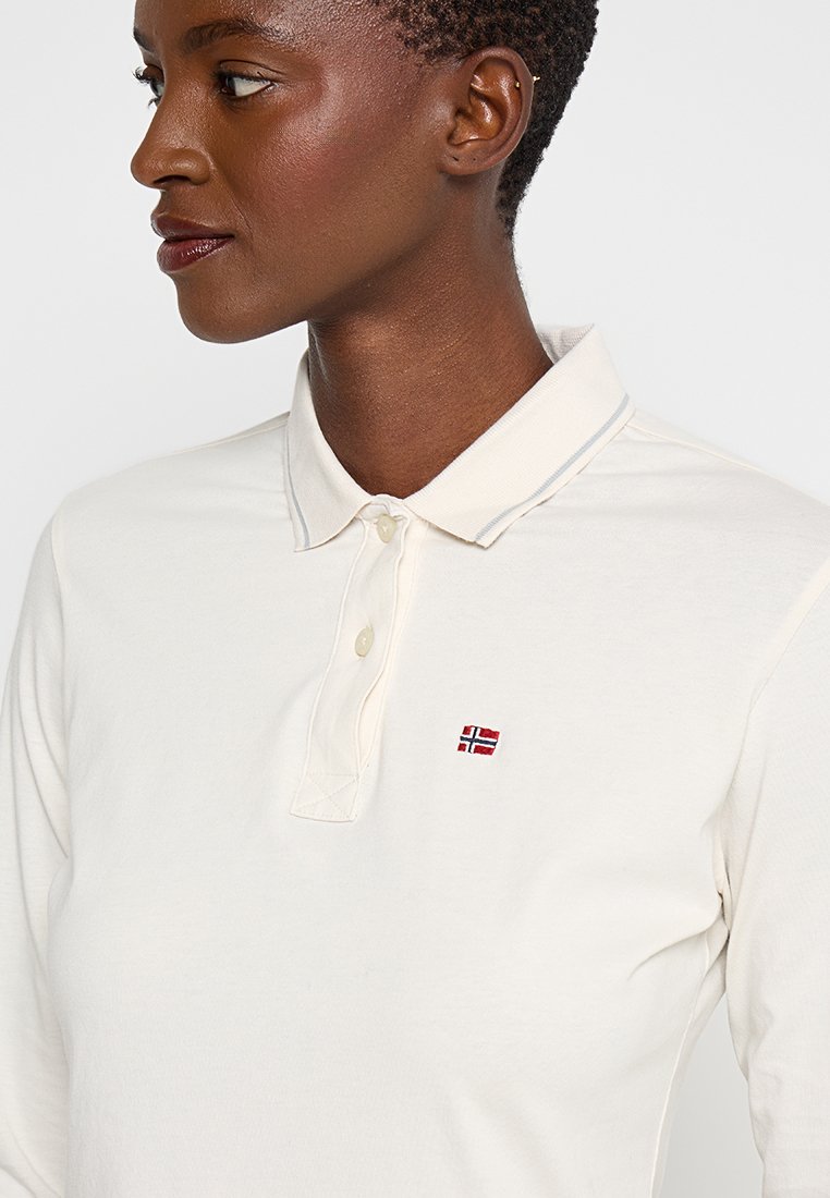 Polo a maniche lunghe di colore crema chiaro realizzato in cotone, con colletto, patta con due bottoni e un piccolo emblema della bandiera norvegese ricamato.