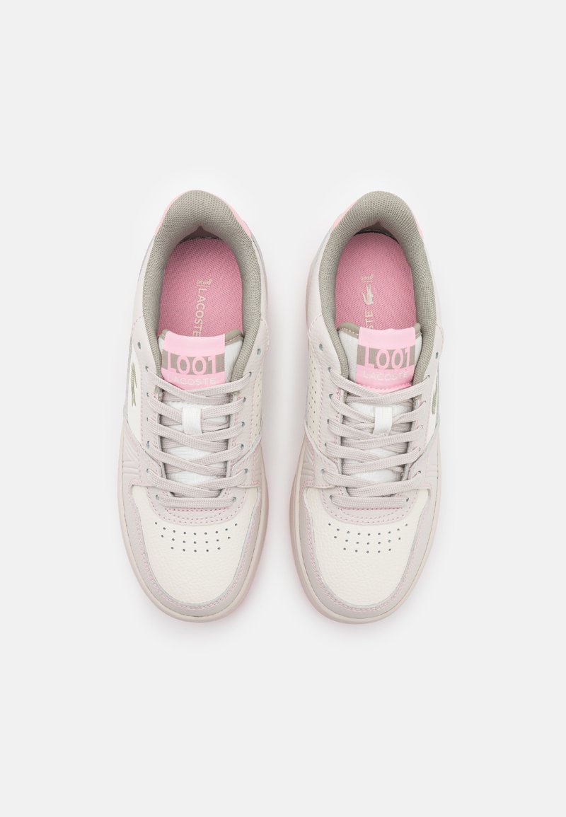 Baskets Lacoste avec une tige en cuir blanc, des accents gris, une languette et une semelle intérieure rose. Présente des perforations sur le bout pour la ventilation.