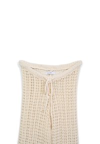 Pull en laine tricoté à mailles ouvertes de couleur beige clair, avec un col rond et un système de fermeture à cordon. Il présente un motif délicat et texturé.