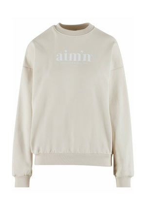 Beige Sweatshirt mit geripptem Rundhalsausschnitt, oversized Passform und elastischen Bündchen. Auf der Vorderseite befindet sich ein weißes Logo mit Text- und Datumsangaben.