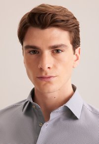 Camicia button-up con un motivo a scacchi bianco e nero in formato piccolo. Caratterizzata da un colletto a punta, polsini standard e una silhouette aderente.