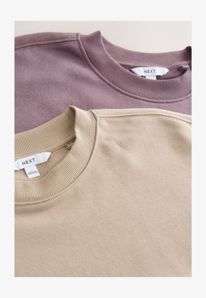 Two sweatshirts in lavender and beige, featuring ribbed necklines and soft textured fabric. Labels are visible at the neck area.