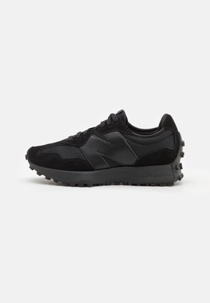 Chaussure de sport noire avec semelle texturée, tige en mesh et daim, fermeture à lacets et grand logo brodé sur le côté, montrée en profil droit.