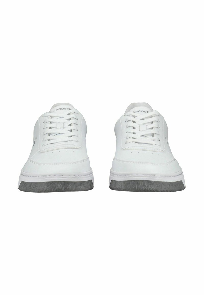 Sneakers bianchi con tomaia in pelle liscia, design con lacci e suola in gomma grigia texturizzata. Logo Lacoste sul lato e sulla linguetta.