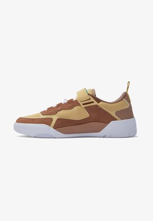 Sneakers med en överdel i brunt ruskinn och gult nät, vit gummisål och ett krok-och-slinga-rem för en säker passform.