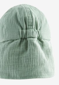 Jasnozielona czapka beanie wykonana z miękkiej, fakturowanej tkaniny. Ma zebrany fason z tyłu oraz subtelne prążkowanie w całym zakresie.