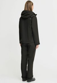Waterproof black jacket with a hood, paired with matching trousers. Features subtle stitching and durable fabric for outdoor wear.