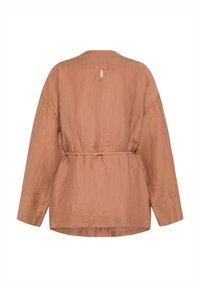 Loszittende, lichtbruine blouse met lange mouwen, een subtiele textuur, een getailleerde taille en een klein roze label midden bovenaan de rug.