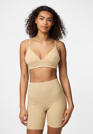 Bež bralette s V-izrezom in tankimi naramnicami, v kombinaciji z visokimi kolesarskimi hlačami, oba izdelana iz gladkega, elastičnega materiala.