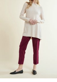 Beige ribbed knit tunic with long sleeves, paired with burgundy tapered pants and black loafers. Plain design, no visible patterns.