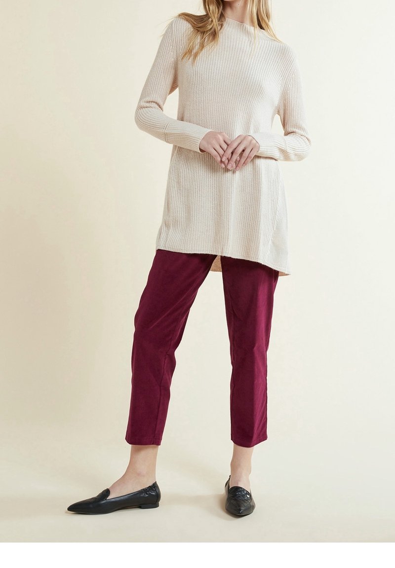 Beige ribbed knit tunic with long sleeves, paired with burgundy tapered pants and black loafers. Plain design, no visible patterns.