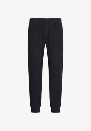 Fekete jogging nadrág, puha anyagból, rugalmas derékpánttal, zsinóros záródással, és rugalmas szegéllyel a bokáknál. Egyszerű dizájn.